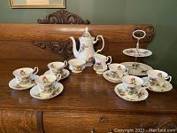Full display of the Royal Albert Highland Thistle tea set with teapot, sugar bowl, creamer, six teacups and saucers, and two-tier serving tray on wooden surface.