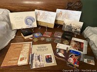 Full overview of lot on wooden surface including booklets, stamp packs, coins in boxes and sleeves, printed cards