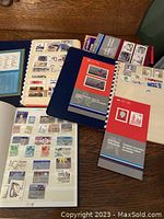 Three stamp album books with visible assorted Canadian stamps on open pages