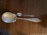 Both spoons laid on wooden surface showing size comparison and decorative designs