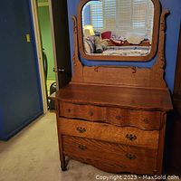 Front view of large antique oak dresser with four drawers and attached mirror.