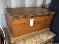 Front and side view of antique wooden blanket box showing dovetail corner joints, aged wood surface and wheels for mobility.