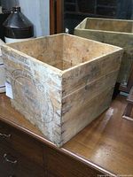 Front and side view of an old wooden butter crate with worn surfaces and faded text, showing the rustic condition and structural details.