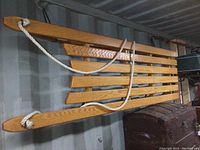 Top view showing the slatted solid oak construction of the sleigh and the white rope handle attached to the front.