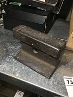 Old railroad track anvil on tabletop with black shoebox background, showing full side and top view