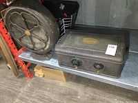 Photo of the Atwater Kent vintage speaker and radio set on metal shelving, showing the side of the speaker and radio front panel.