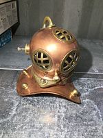 Front angle photo of replica copper and brass diver's helmet showing the front windows and base.