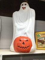 Full front view of vintage plastic ghost blow mold with an orange jack-o-lantern pumpkin, showing ghost's face and pumpkin details.