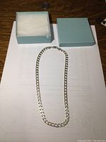 Sterling silver chain displayed alongside a light blue gift box with white padding, showing the full chain length of 16 inches.