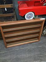 Front view of rectangular wooden display case with four shelves and model train tracks, no trains inside