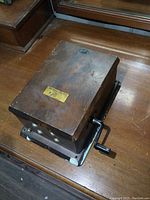Angled photo of the top and side of a wooden antique phone ringer box showing the crank handle and the 'Northern Electric' label.