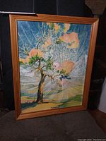 Framed watercolour painting showing full artwork including tree, sky, and sunburst effect with pink clouds.
