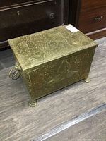 Top and side view of the rectangular brass ash box showing textured hammered surface and ornate decorative patterns with hinged lid.