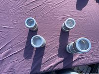 Top-down view of ten metal magnetic spice holders arranged on a purple cloth surface, showing front opening with clear lids.