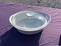 Oval white ceramic CorningWare bakeware dish with clear glass lid.
