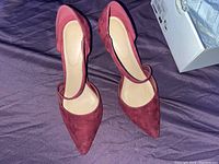 Top view of the pair of burgundy suede pointed high heel shoes with a strap.