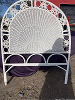 Front view of white wicker single headboard showing semi-circular woven pattern and tubular frame with scrollwork accents.