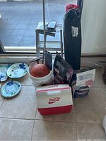 Wide shot showing most items including cooler, plates, bucket with basketball, charcoal bags and poles