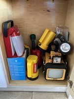 Shelf with six flashlights and a boxed telephone, various styles and sizes.