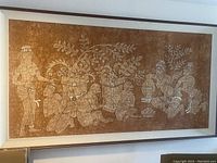Full view of large Indonesian wall art depicting traditional figures and large planter, framed in wood.