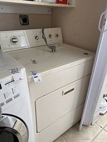 Full view of white KitchenAid dryer next to another appliance, showing control panel and part of the laundry space.