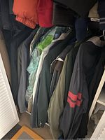 Photo showing 9 men’s jackets arranged on a hanging rod in a closet, various colors and styles visible.