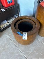 Large wooden planter with a medium planter inside it, placed on tiled floor near furniture.