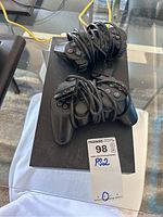 Top view of PlayStation 2 console with two wired controllers coiled and placed on top, showing controller buttons and ports on console front.