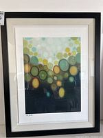 Full view of the framed abstract art print with multicolored circular pattern.
