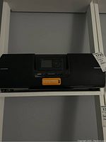 Front view of the black SiriusXM radio with central screen and buttons, built-in speakers visible at each end.