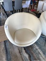 Front view of white leather swivel chair showing round back and seat cushion.