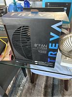Photo showing boxed Treva 8-inch 2-speed fan, battery and adapter powered, unopened retail packaging with visible branding.
