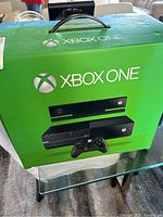 Front and side views of the Xbox One retail box showing console, Kinect sensor, and controller images