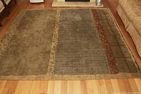 Full view of the woven wool rug laid flat on wooden floor with visible color and pattern details