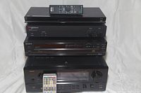 Front view of stacked AV components: Sony Blu-Ray player, AudioSource amplifier, Sony CD player, Denon AVR-4800 receiver with remotes on top and front.
