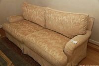 Front side view of beige couch with rolled arms and patterned upholstery.