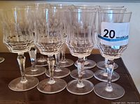 Twelve clear hand made Galway cut glass water glasses showing textured vertical cut design, placed on wooden table.