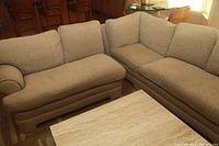 Front view of two-piece sectional couch arranged inside a room near wooden furniture and a coffee table.