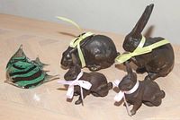Photo depicting four cast metal rabbit sculptures with ribbon bows and one glass angel fish sculpture with striped design.