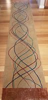 Runner wool rug with a beige background and intersecting multicolor wavy lines, shown flat on hardwood floor.