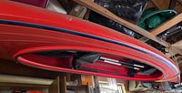 Red kayak hanging from ceiling, showing side profile and cockpit
