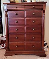 Front view of Keller 7-drawer wooden dresser showing round knobs and decorative carved columns on corners with a warm medium brown finish.