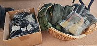 Photo of a box and basket containing new gloves, mittens, and caps in various colors and fabrics, some in packaging.