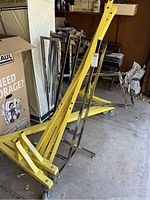 Photo of two yellow metal bases with wheels and chrome vertical support frames stacked in garage.