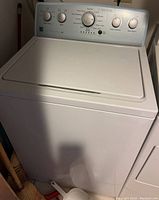 Front and top view of a white Kenmore top-loading clothes washer showing control dials and lid.