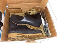 Photo of brown rubber boots with lug soles inside an open cardboard box, showing one pair of Lacrosse men's size 13 waders.