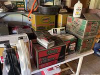 Wide shot of assorted motor oil jugs and cases on workbench