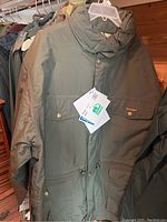 Green Remington parka on a hanger with tags visible