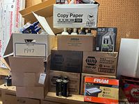 Boxed new motor oil bottles, both Mobil 1 and NAPA Full Synthetic brands visible, stacked with some air filters.