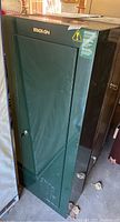 Front angle view of tall green Stack On safe showing general condition and locked door with key included.